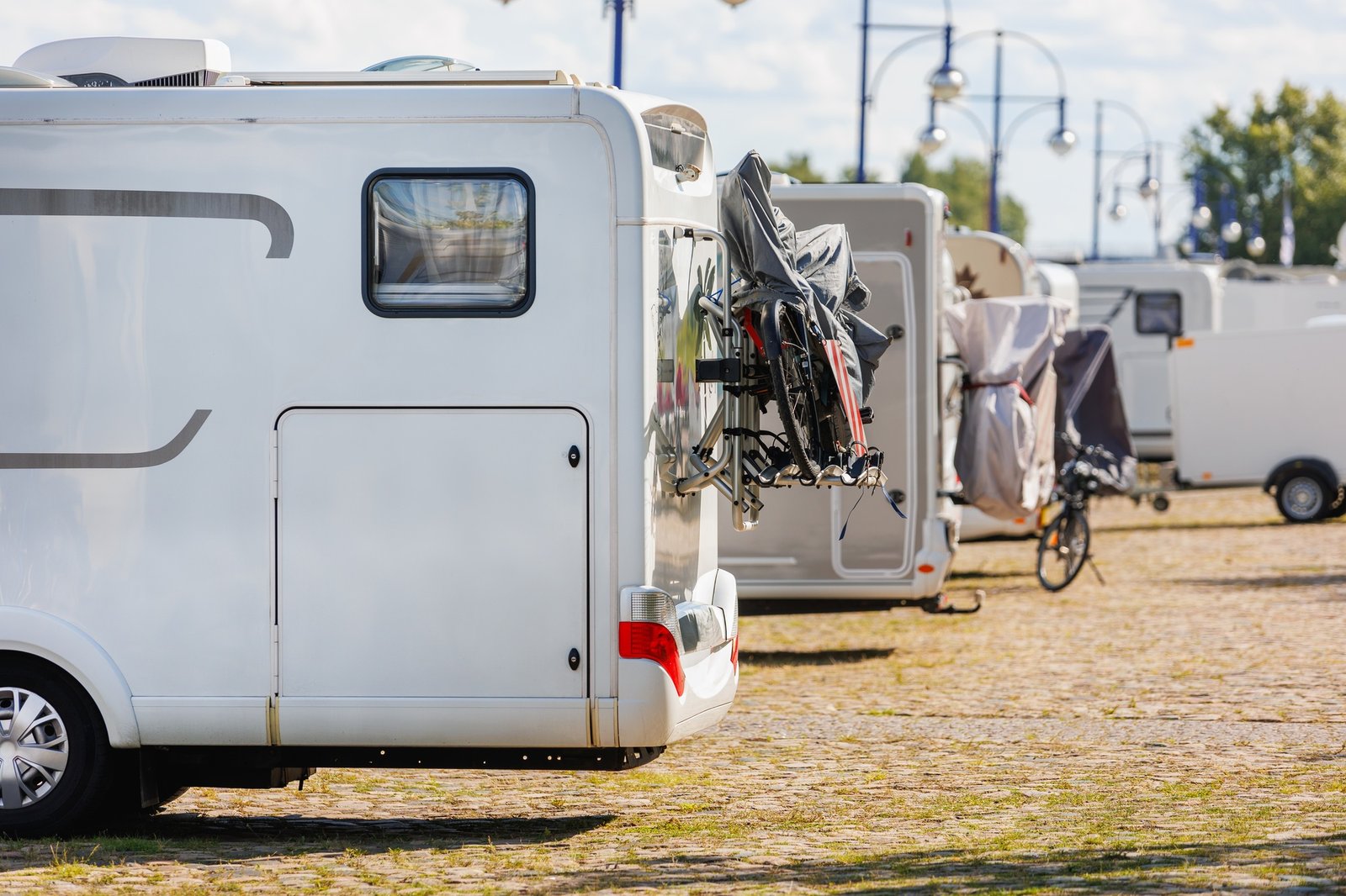 Many white modern campervan recreational motor home vehicles parked in row at camper park site
